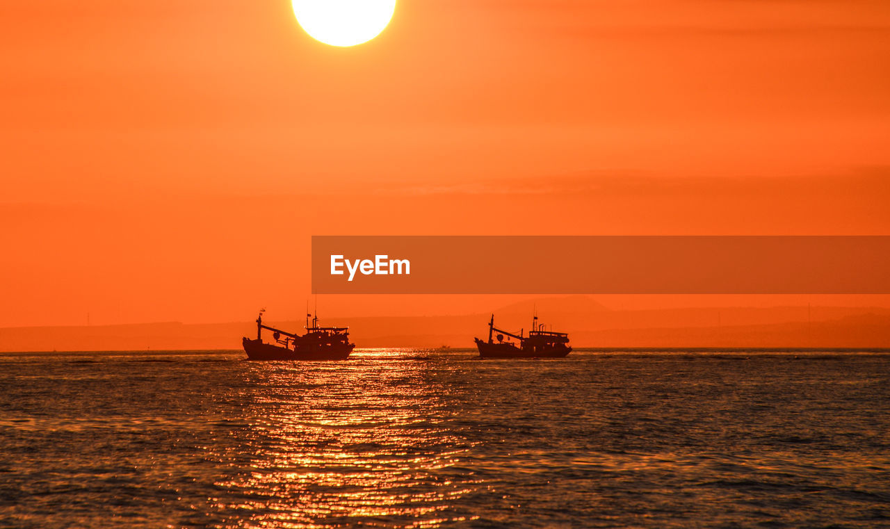 Two fishing boats against sunset