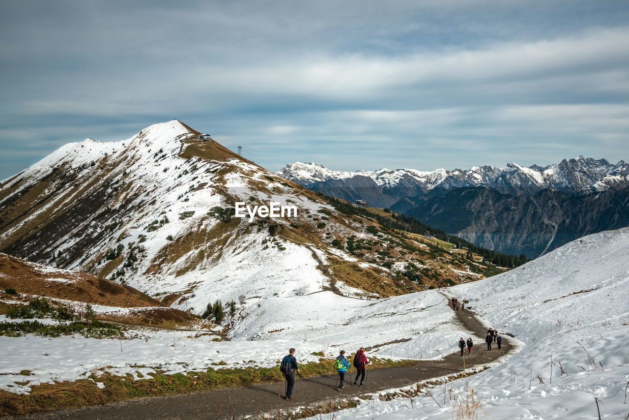 PEOPLE WALKING ON SNOWCAPPED MOUNTAINS AGAINST SKY