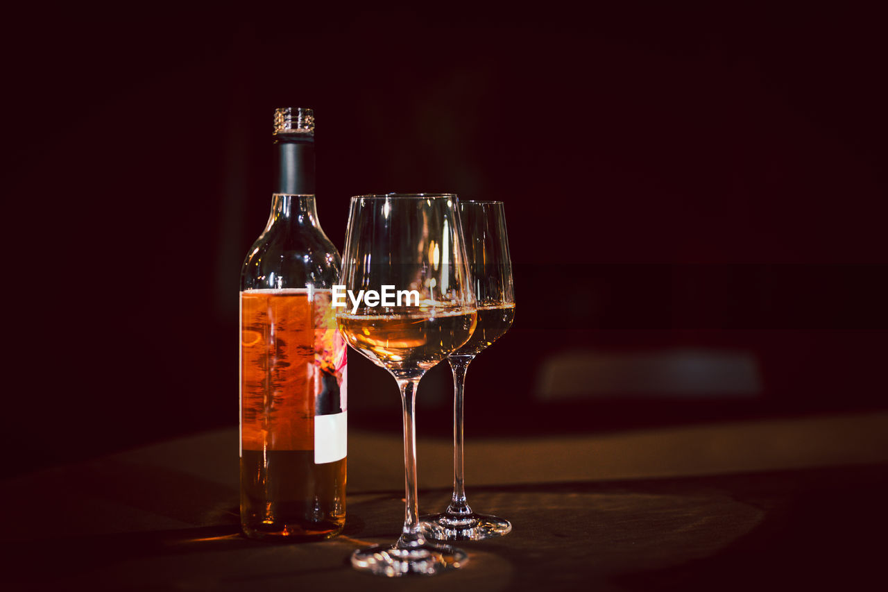 Glasses and bottle of rose wine on dinner table.