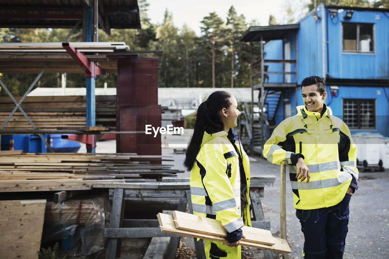 Happy carpentry students in reflective clothing talking outside school