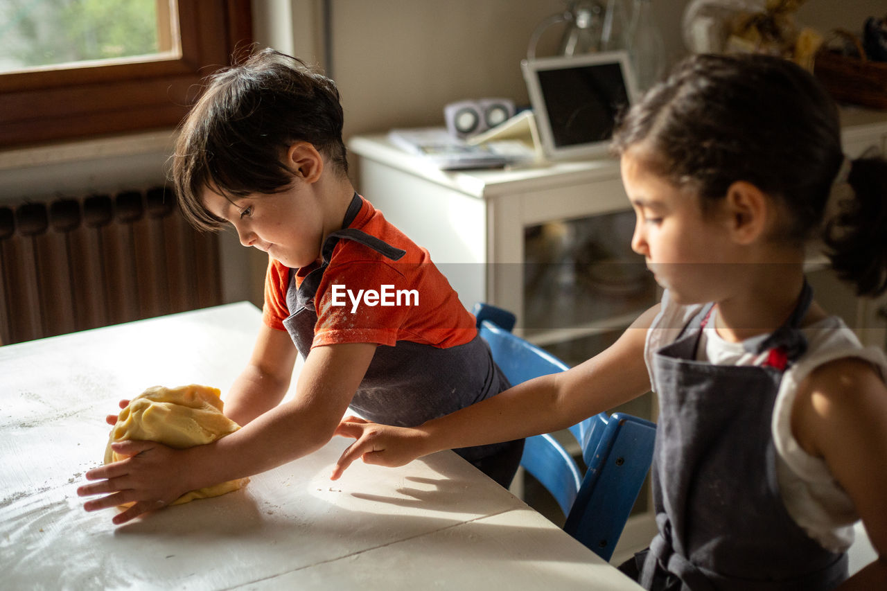 Little girls with dark hair preparing the dough