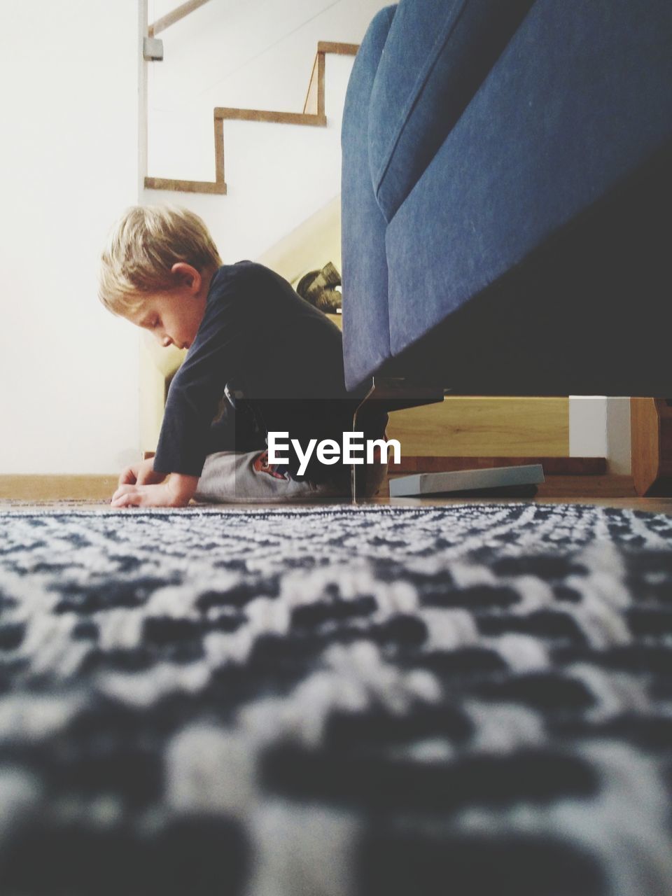 Cute boy playing while sitting on floor at home