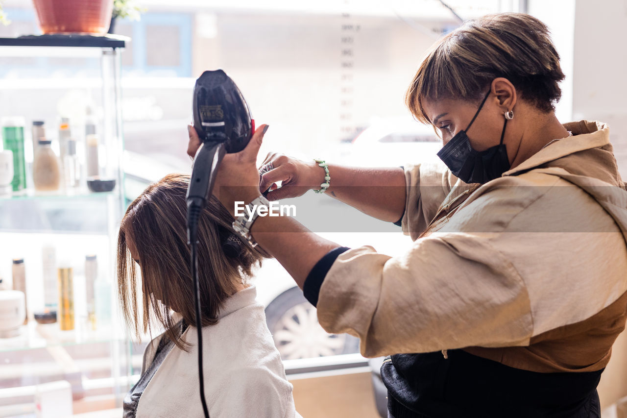 Hairdresser styling customers hair at salon