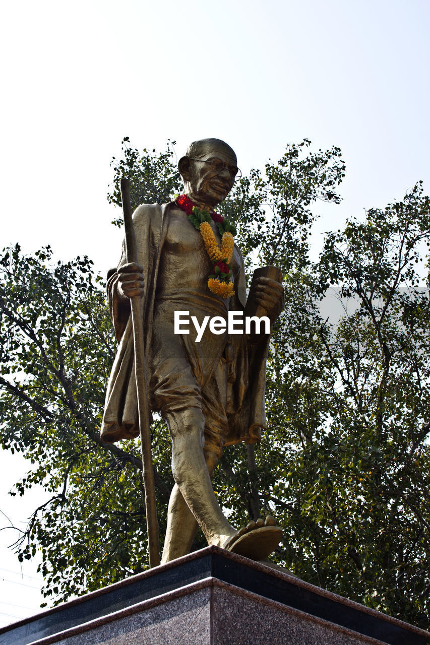 LOW ANGLE VIEW OF STATUE AGAINST TREES