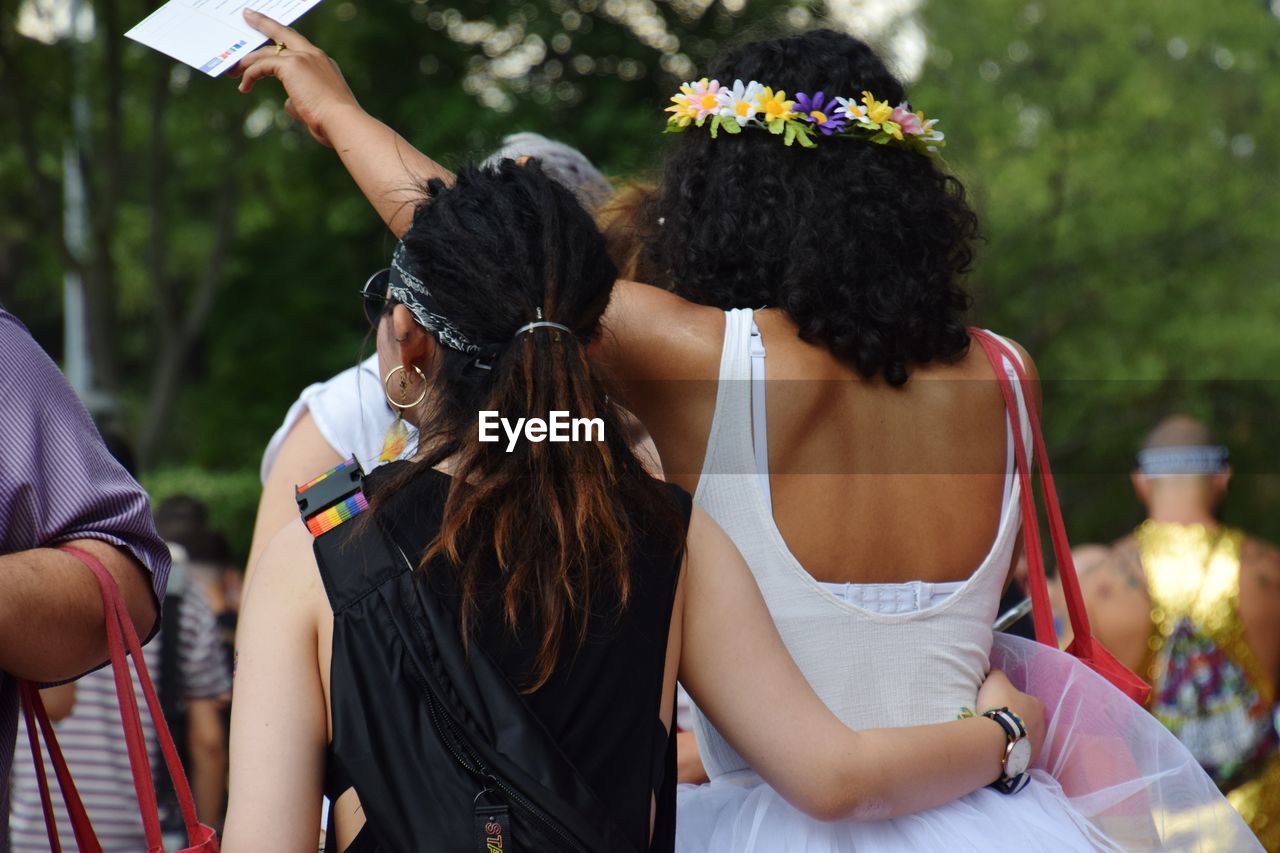 REAR VIEW OF WOMEN STANDING ON A MAN PHOTOGRAPHING