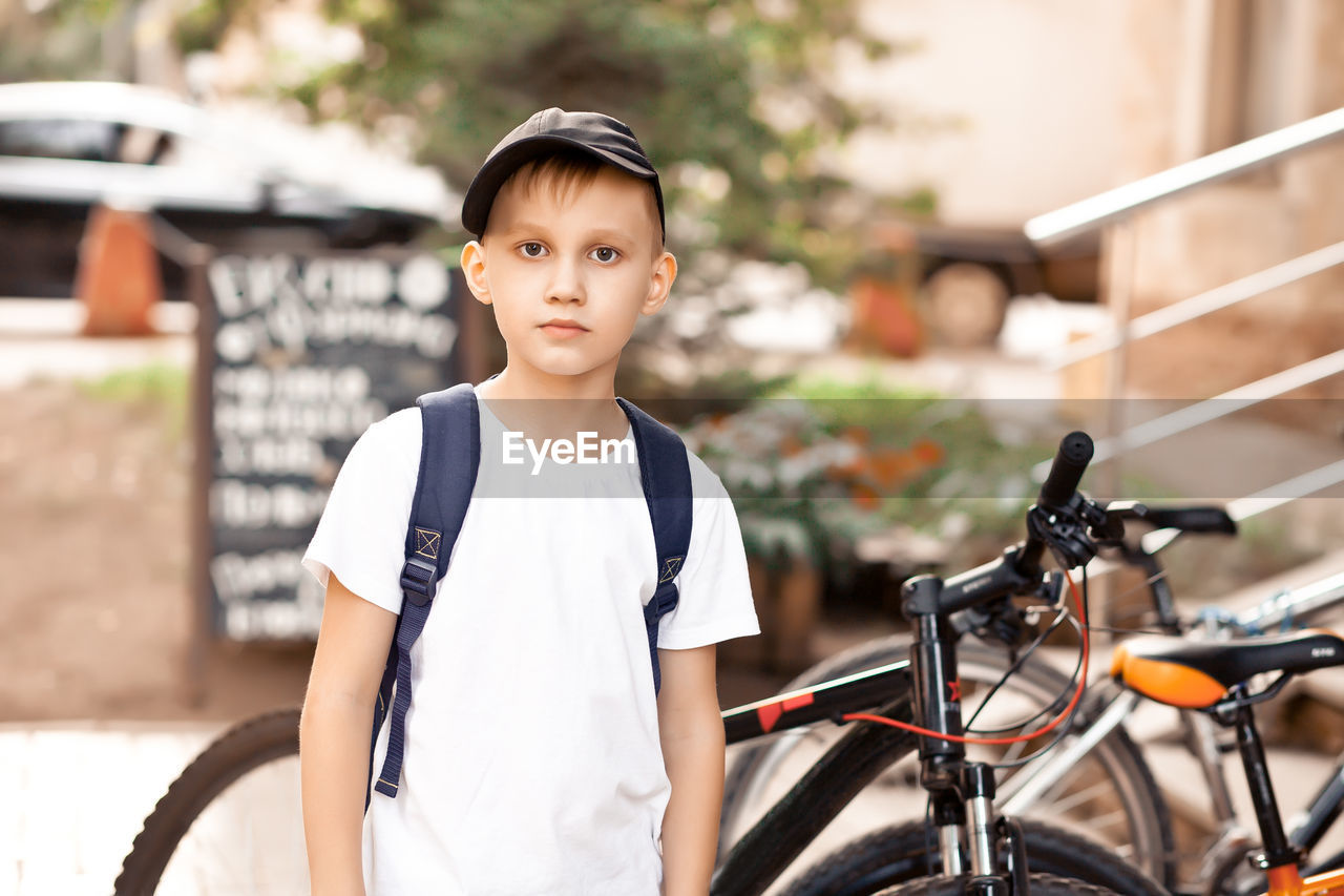 Boy in cap standing near by bicycles