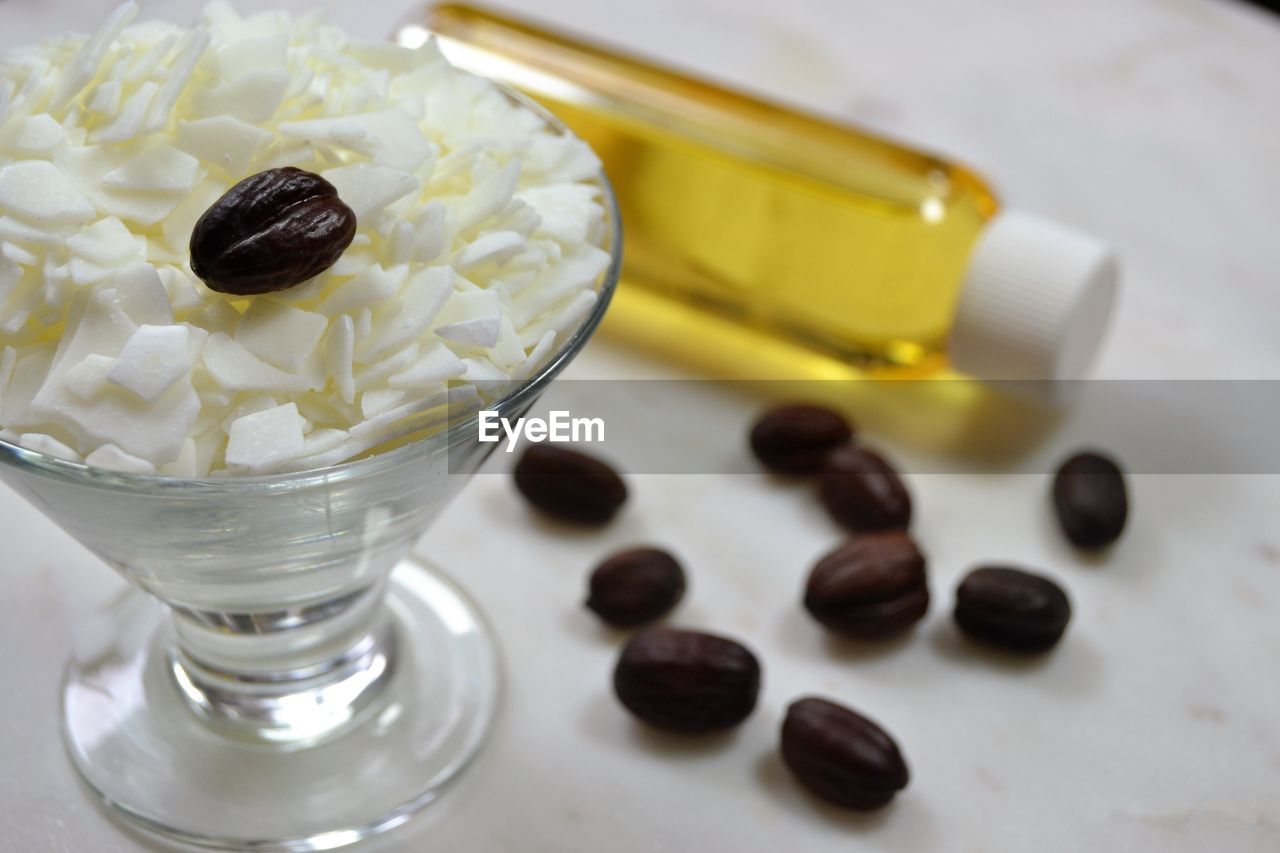 Close-up of jojoba seeds with oil and flakes on table