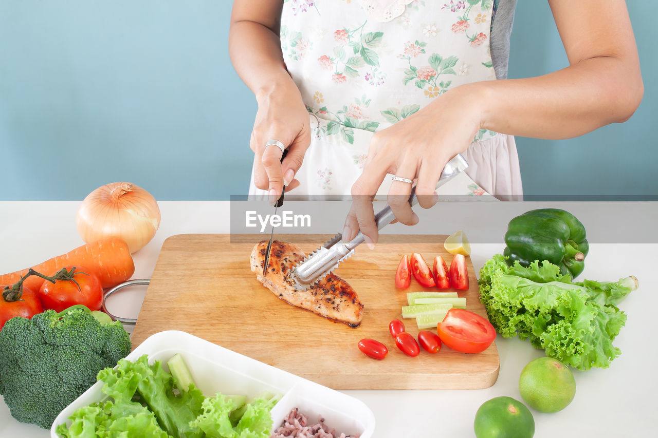 MIDSECTION OF WOMAN PREPARING FOOD ON TABLE