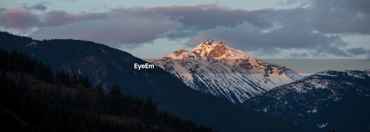 The sun sets on snow covered mountains on a spring day in the coast mountains of british columbia.