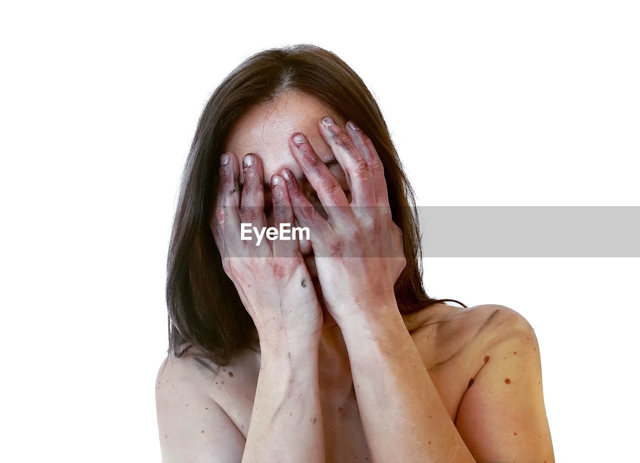 Shirtless woman with hands covering face against white background