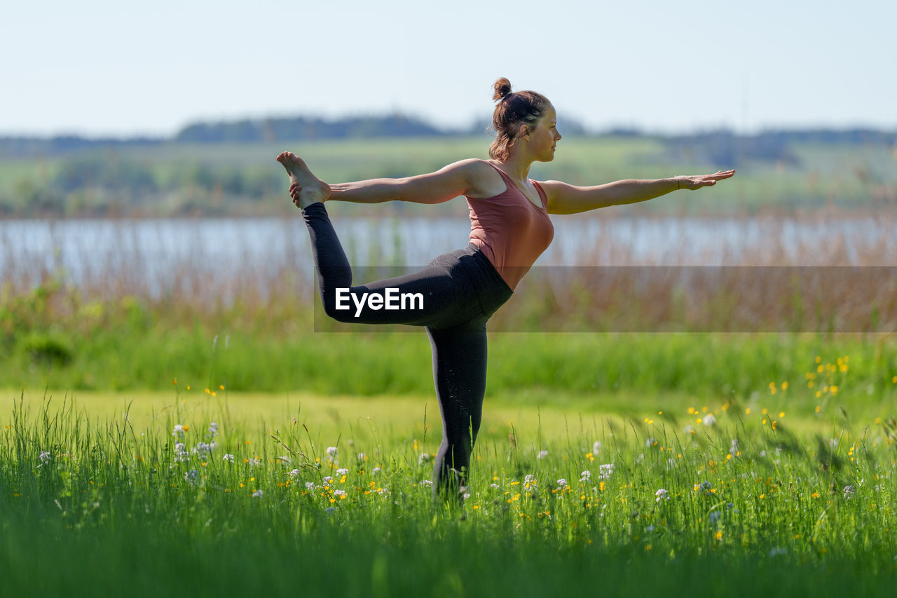 Woman doing yoga poses outdoors in summer near lake