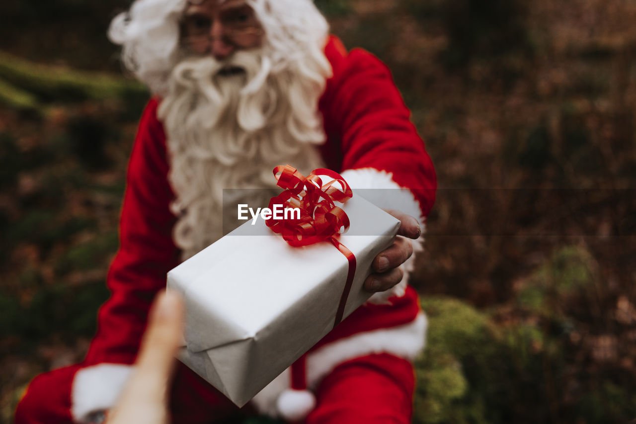 Man wearing santa costume holding present