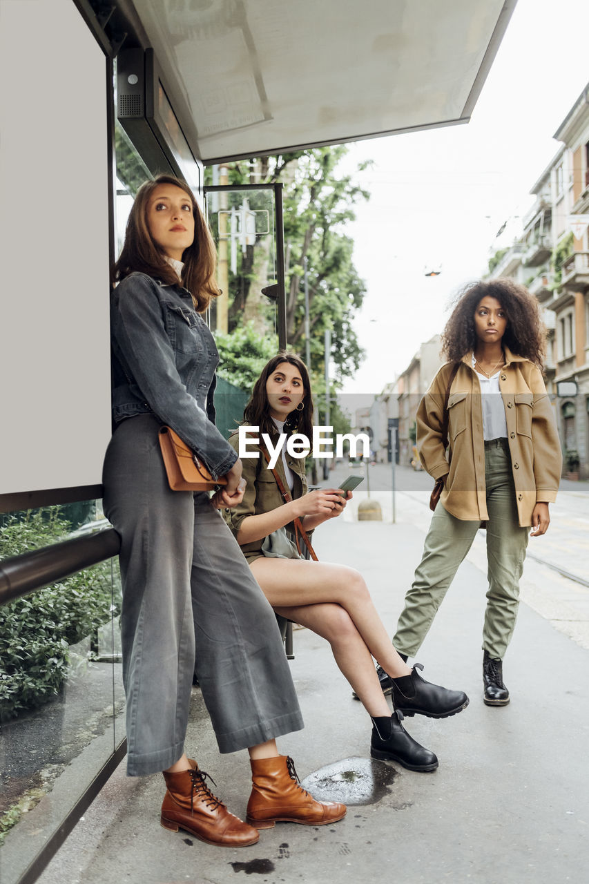 Young women waiting while standing at bus stop