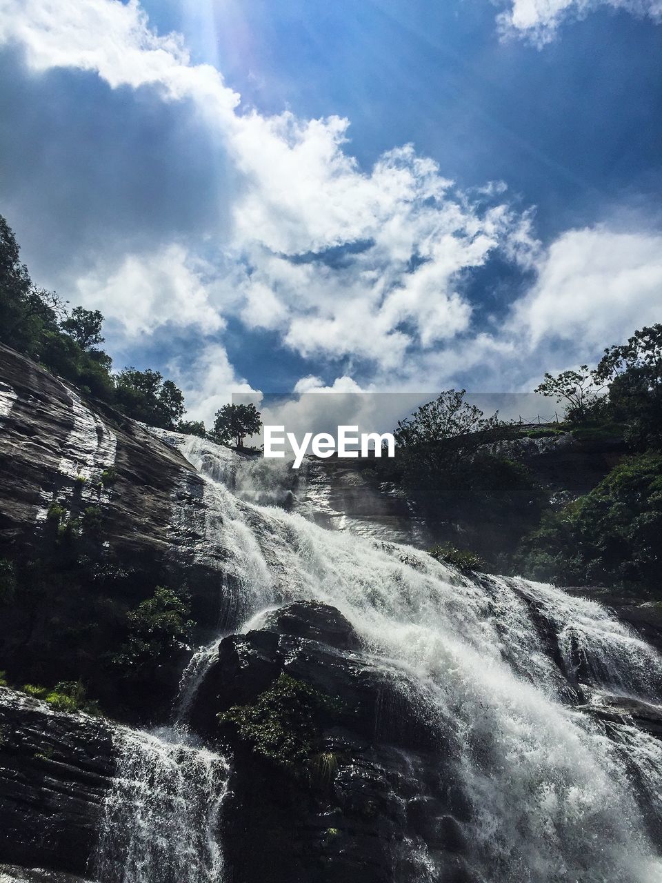 Low angle view of waterfall on mountain against sky