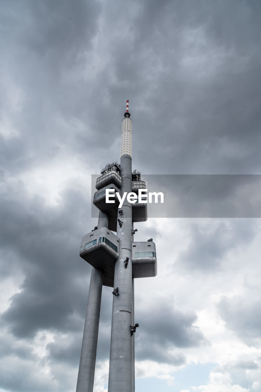 Low angle view of communications tower against cloudy sky