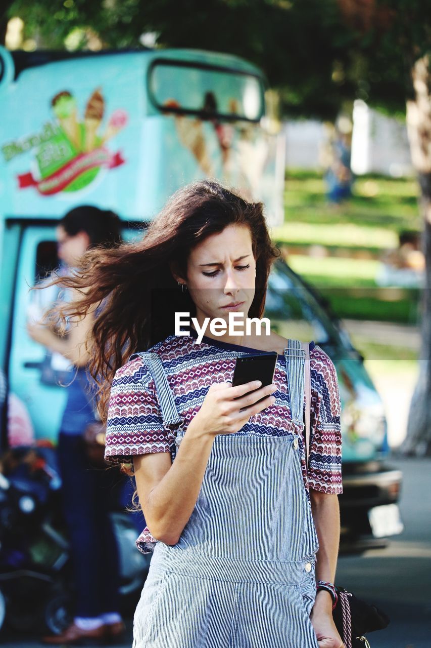 Young woman using mobile phone on road