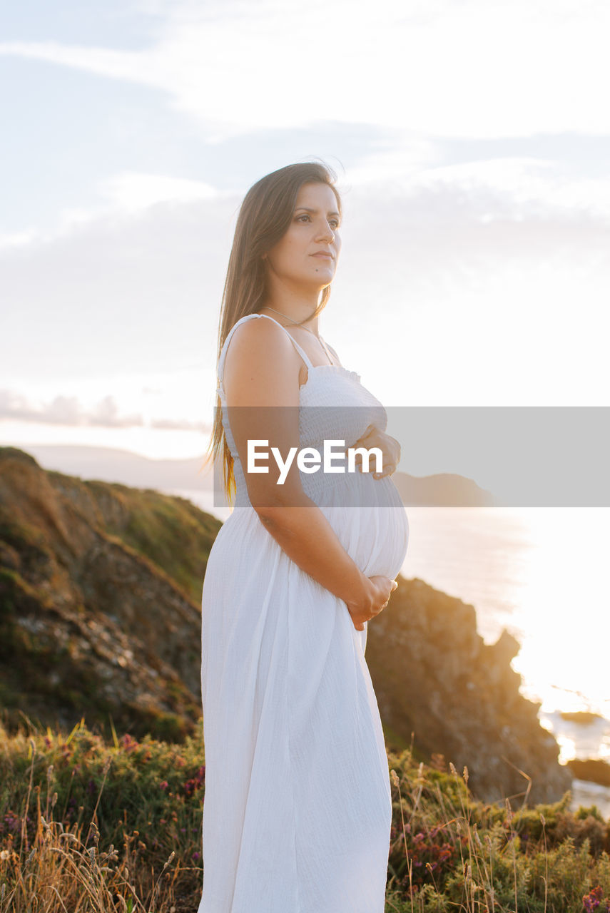 Side view of woman standing on land against sky