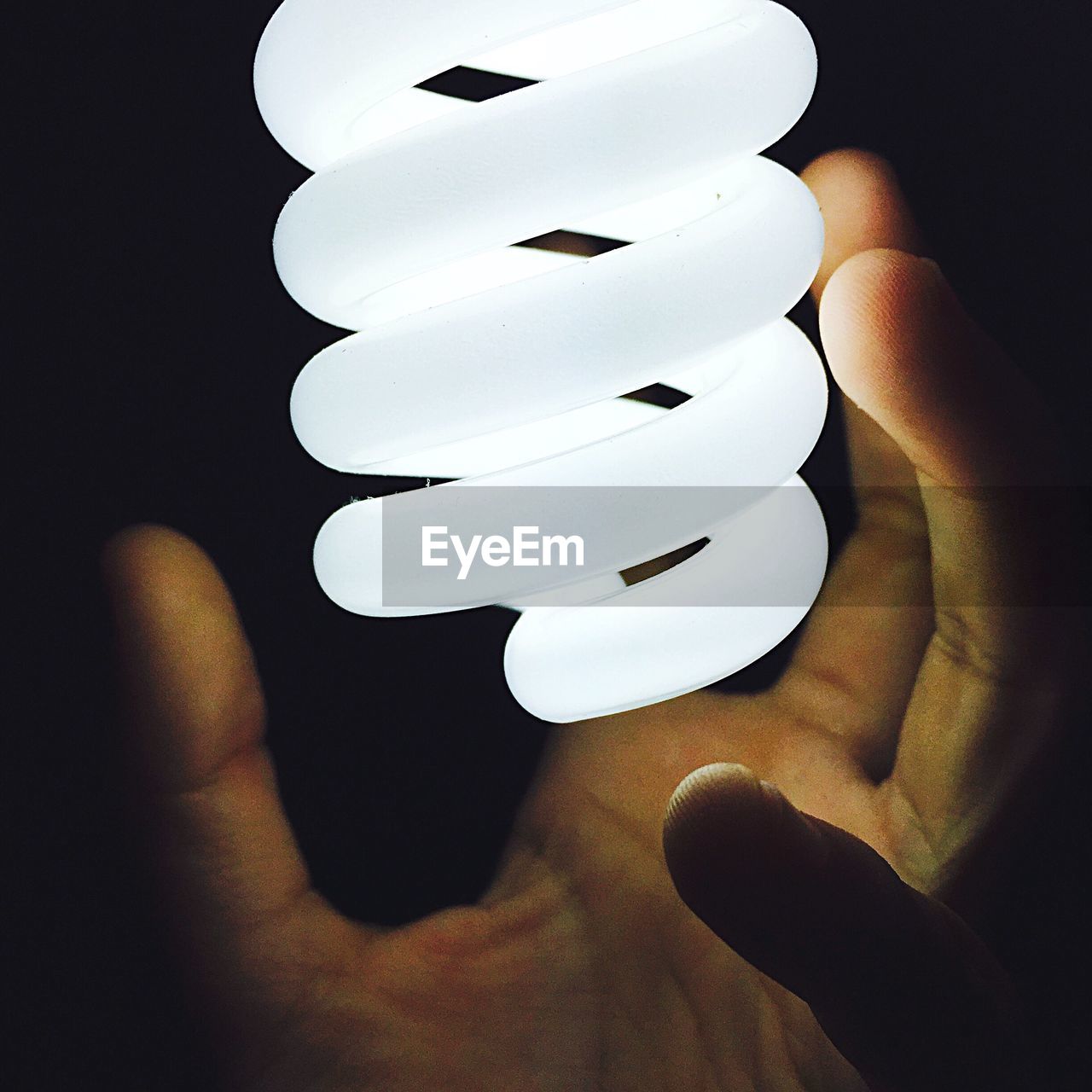 Low section of person holding light bulb