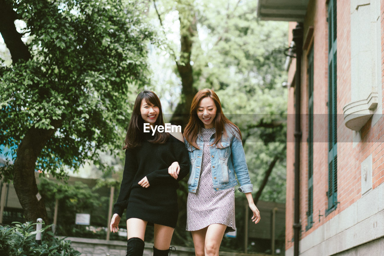 Smiling young woman walking with friend by building