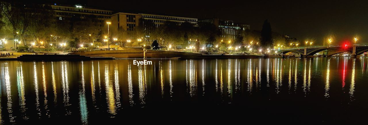 ILLUMINATED BRIDGE OVER RIVER IN CITY