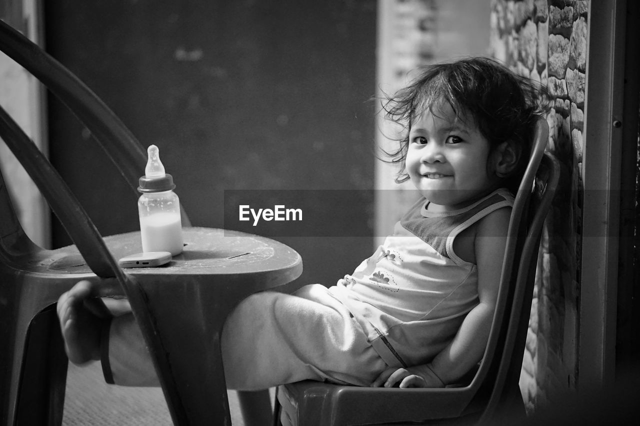 Portrait of cute baby girl sitting on chair at home