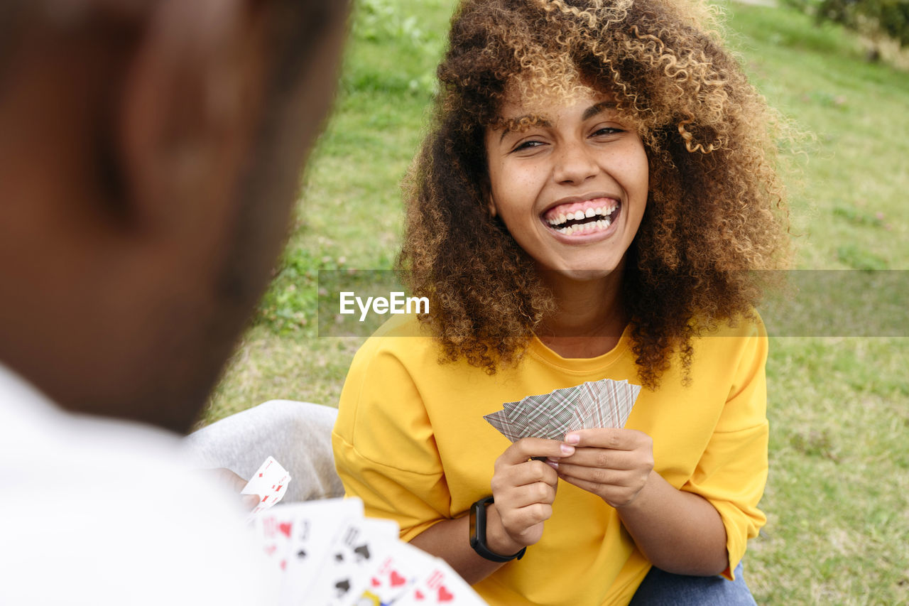 Woman laughing and playing cards with friend in park