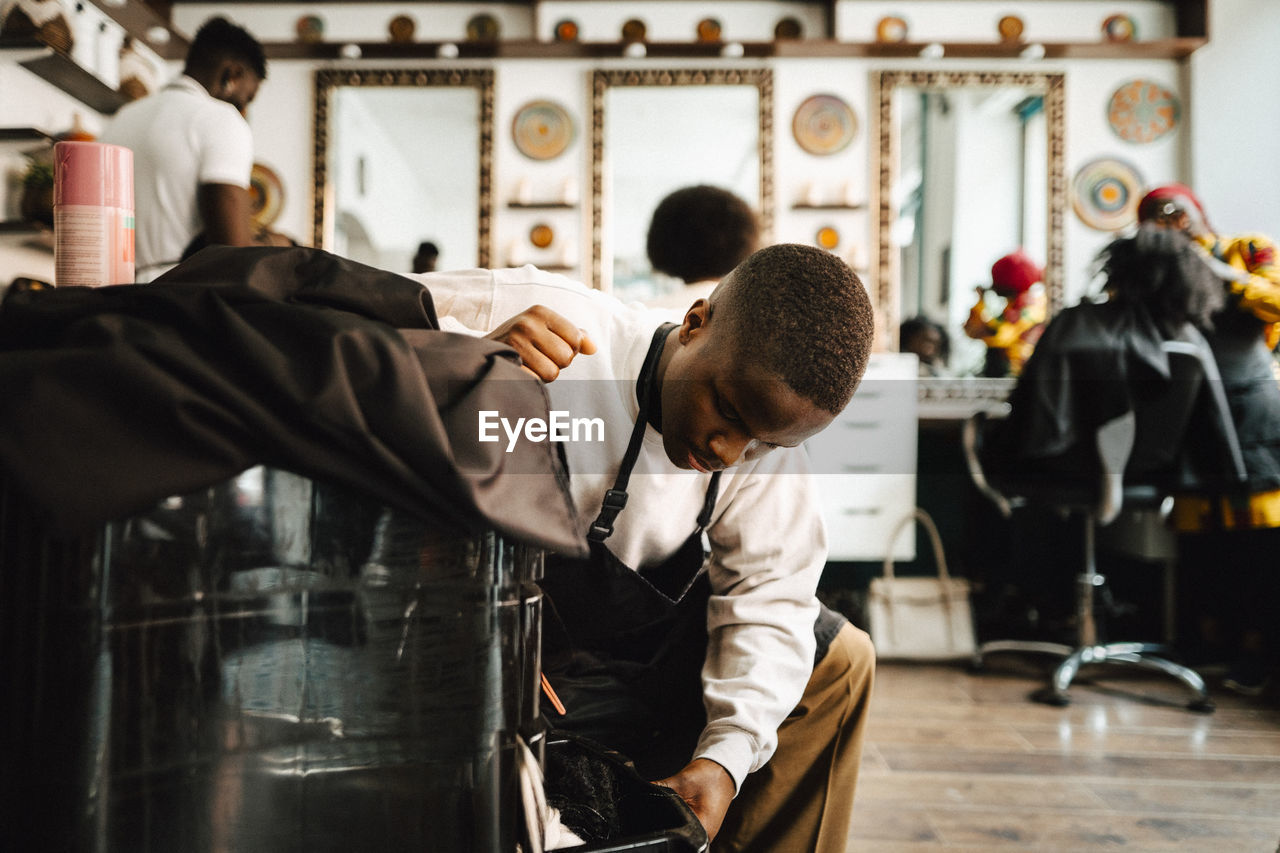 Young male barber opening drawer in hair salon