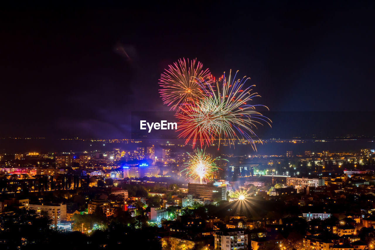 High angle view of firework display over city at night