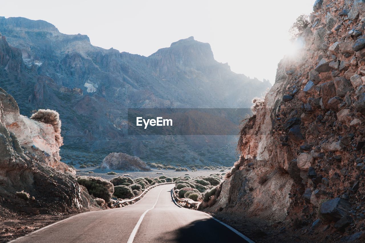 Road leading towards mountains against sky