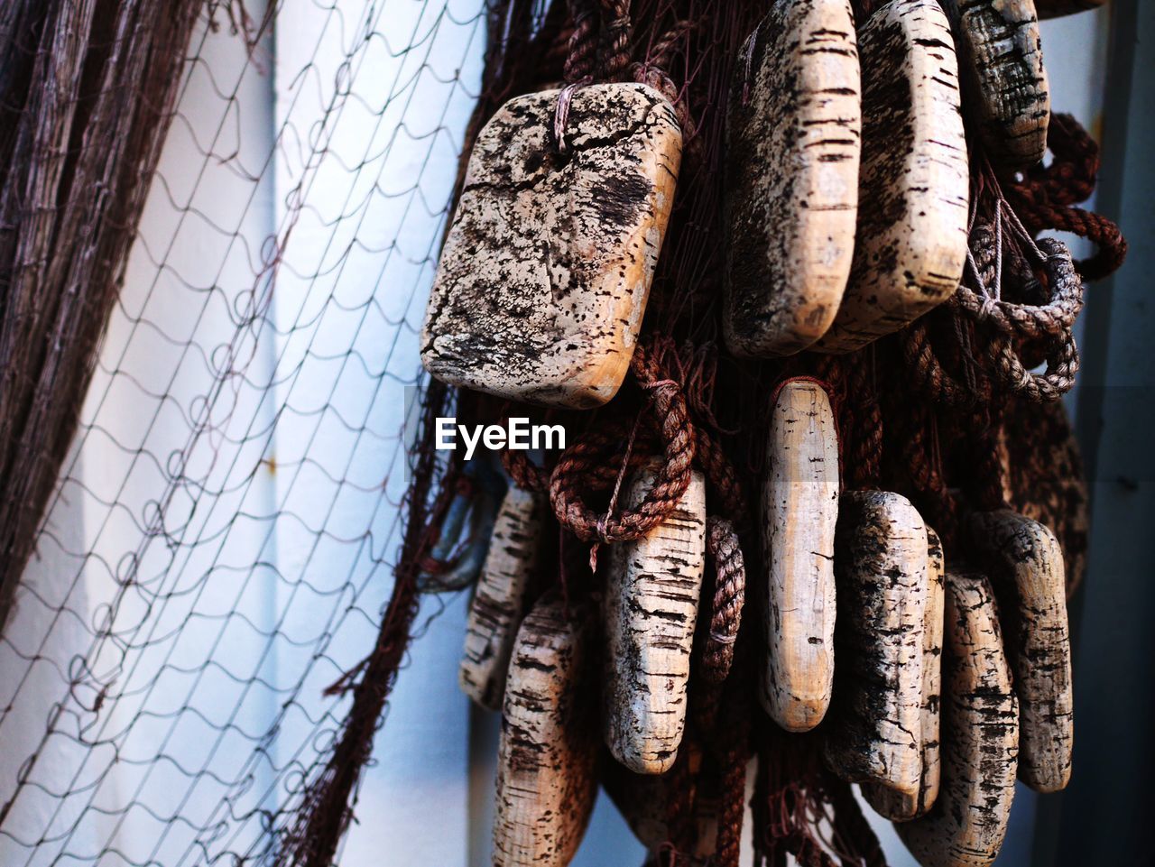 Close-up of fishing net with buoys by wall