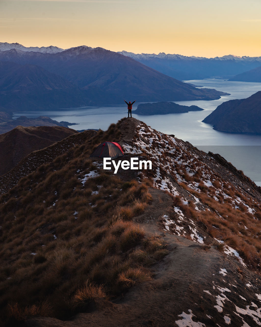 Rear view of man standing on mountain during sunset