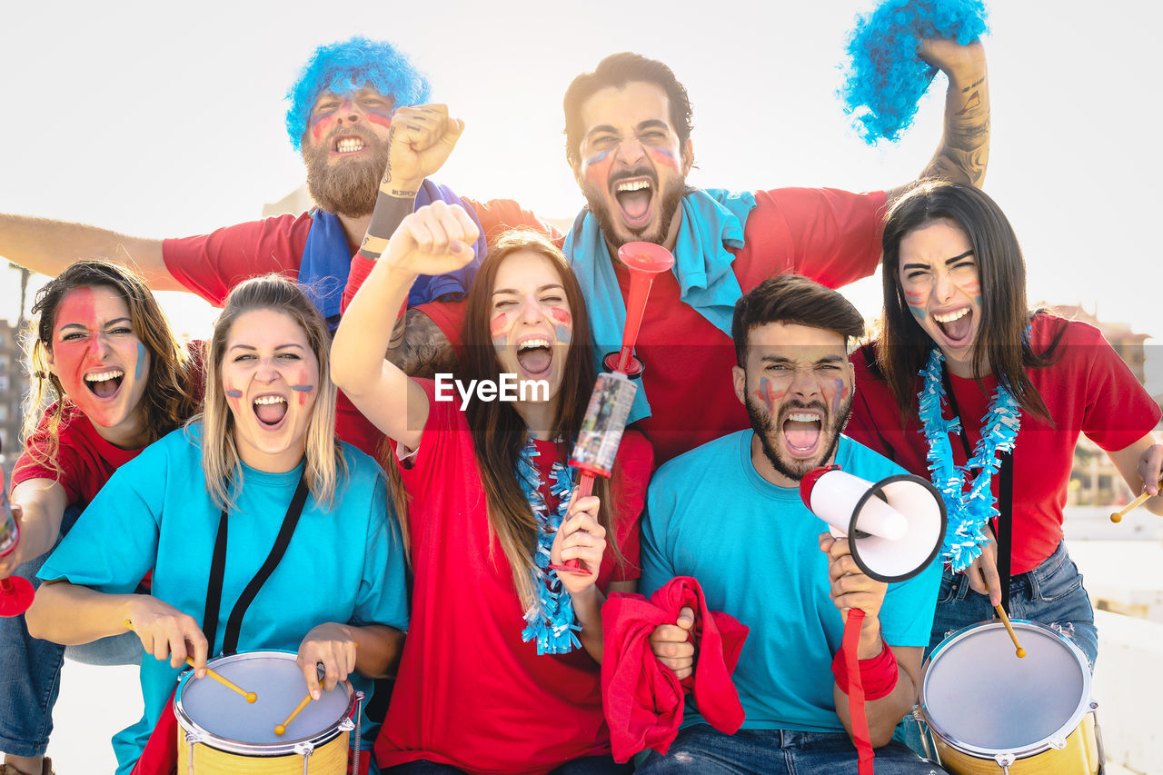 Portrait of fans screaming outdoors