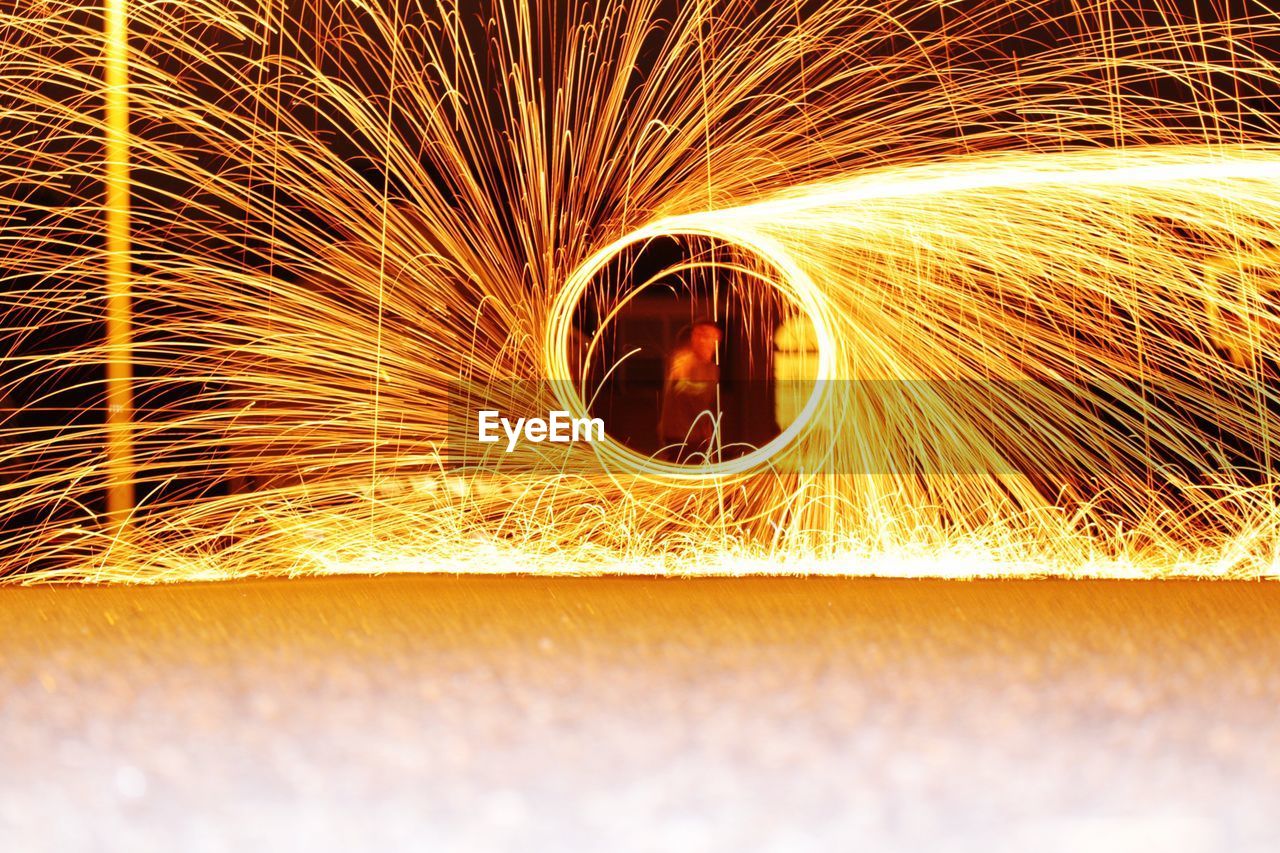 Man spinning illuminated wire wool at night