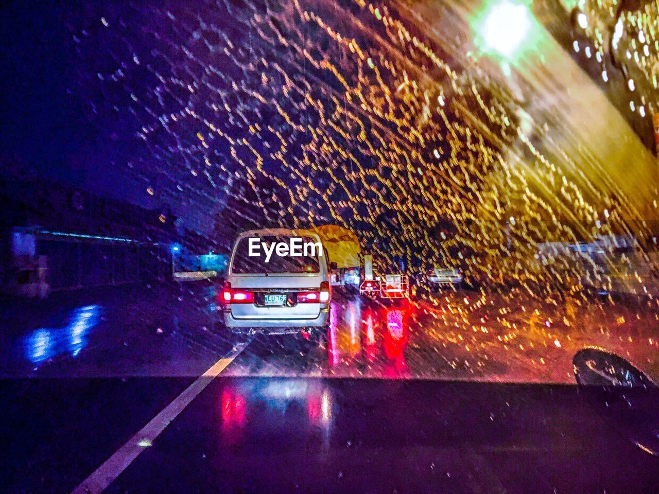 REFLECTION OF ILLUMINATED CAR ON ROAD