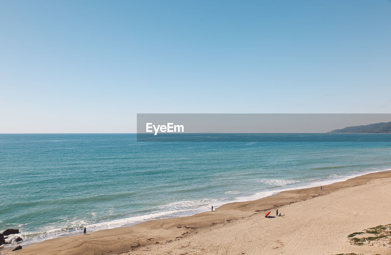 Scenic view of beach against clear blue sky