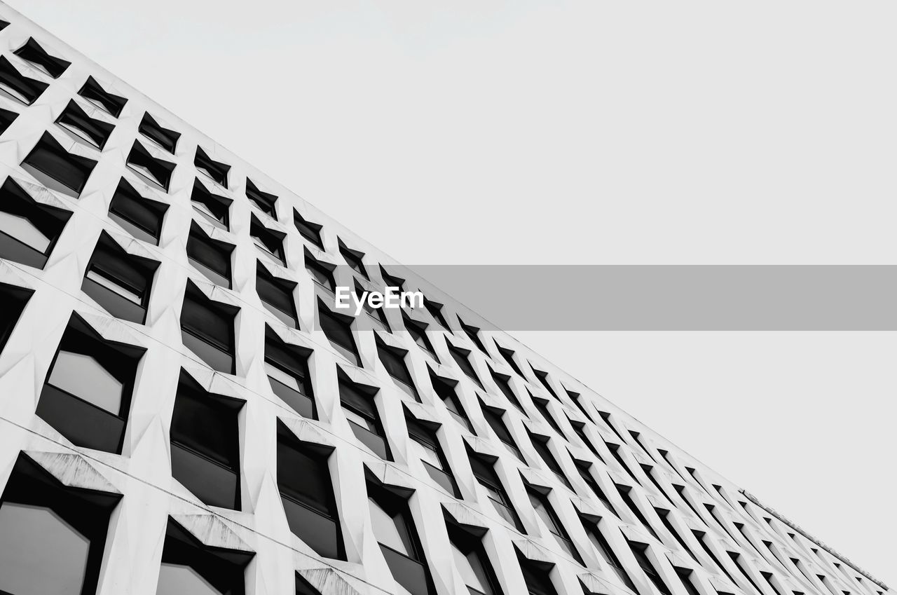 Low angle view of modern building against clear sky in black and white 