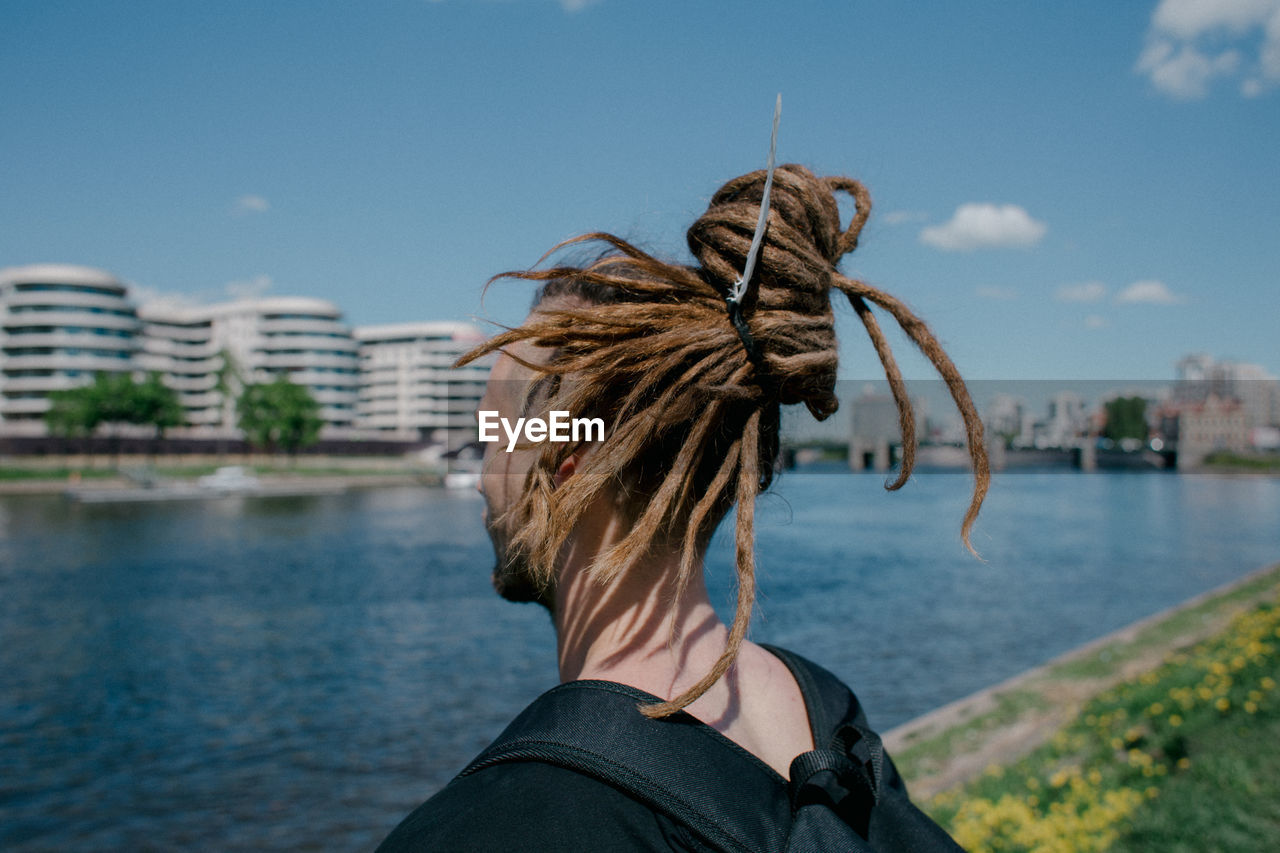 Close-up of man with dreadlocks standing by river in city