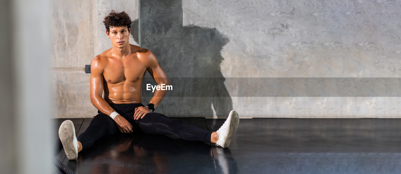 Full length portrait of man sitting in gym