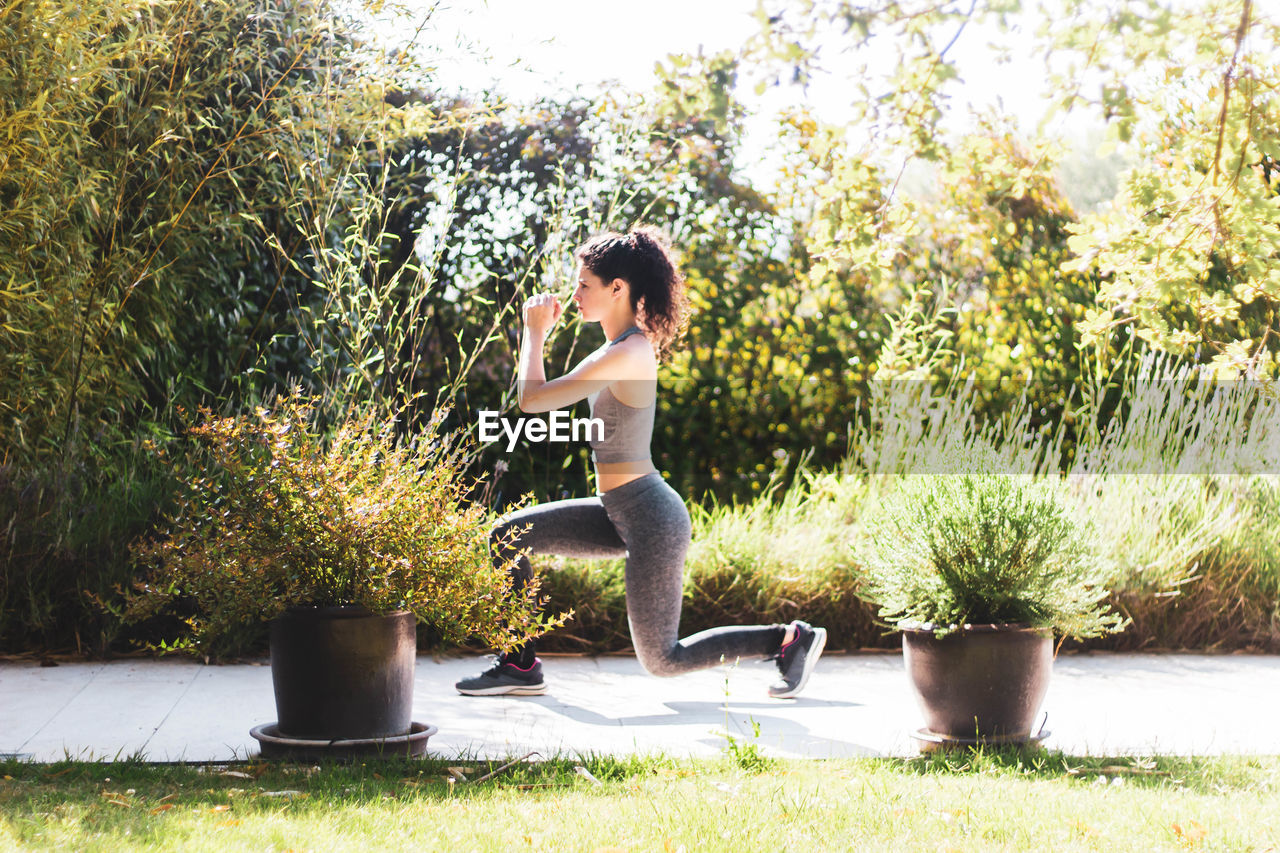 Young woman exercising in her home garden