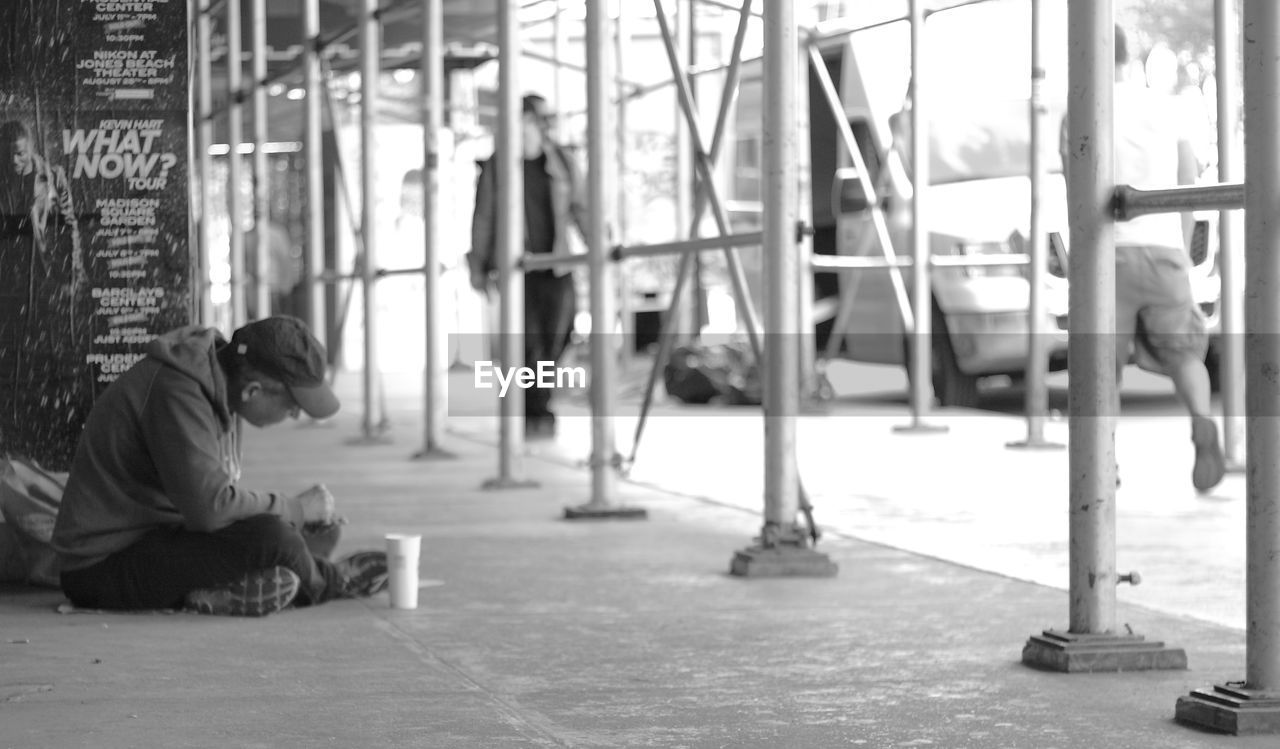 REAR VIEW OF WOMAN SITTING ON BENCH