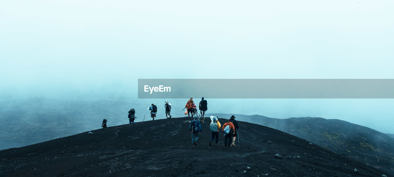 People hiking on mountain during foggy weather