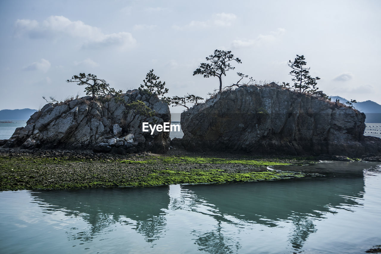 Rock formation in lake against sky