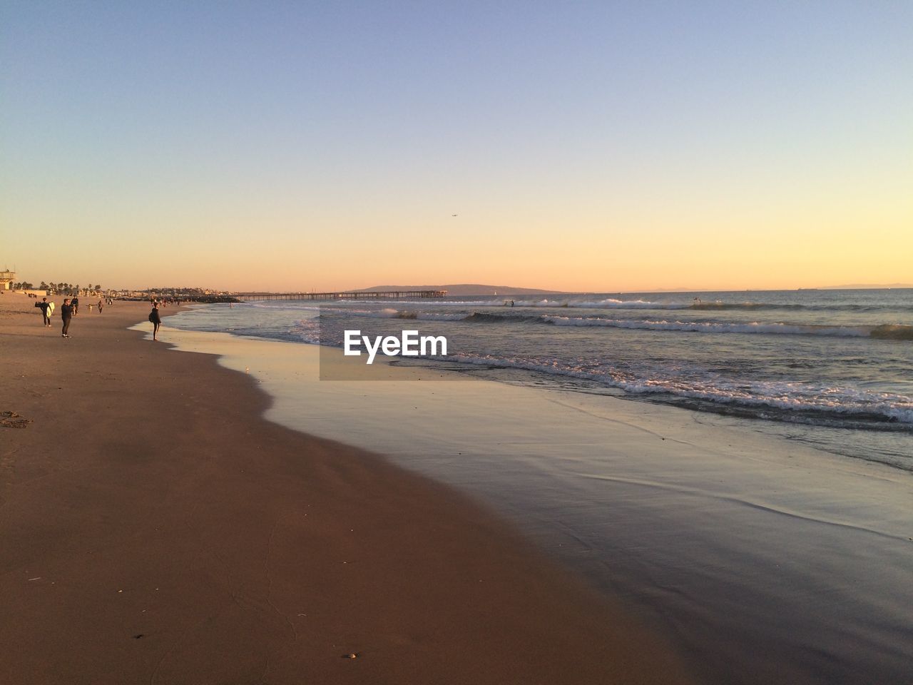 Scenic view of beach against clear sky during sunset