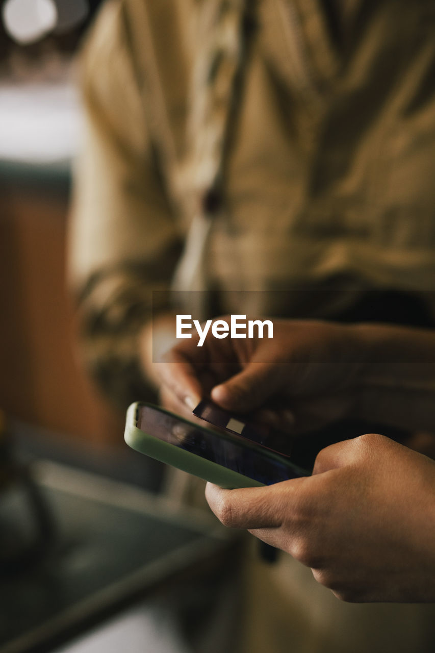 Cropped image of customer paying through credit card at repair shop