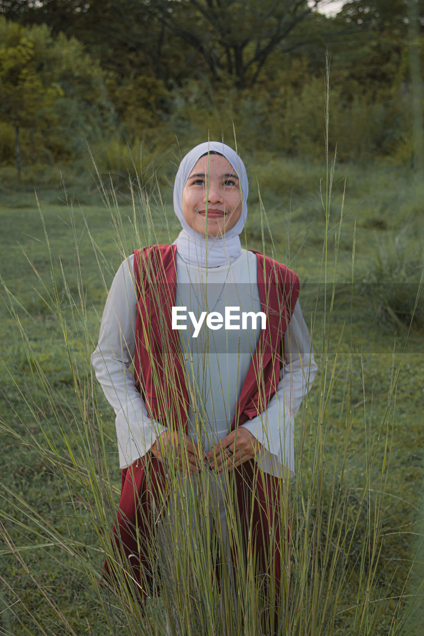 Portrait of smiling young woman standing on field