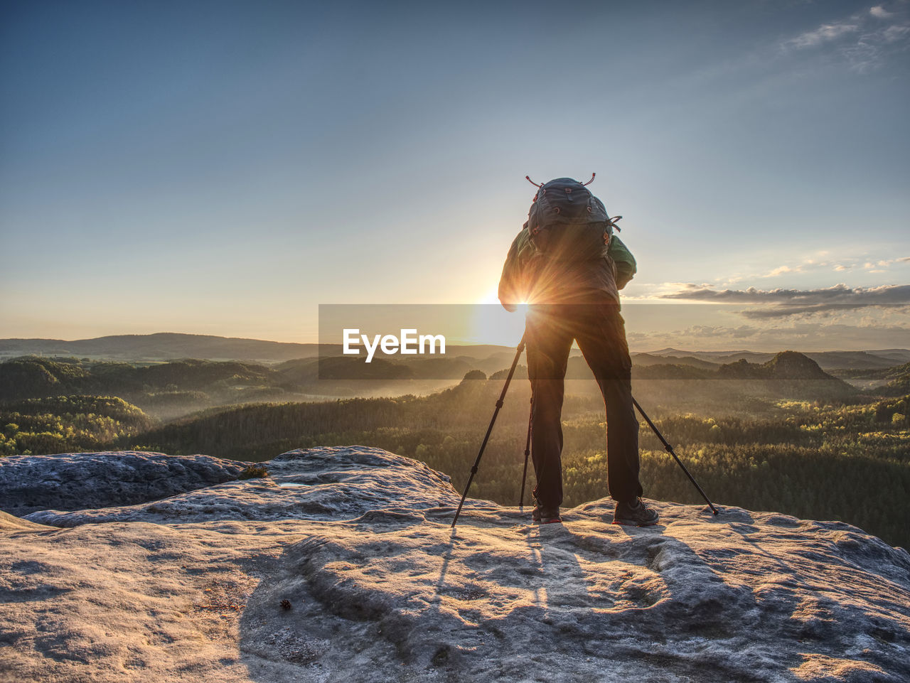 Artist set camera and tripod to photograph the sunrise on a rocky summit. artist works in nature