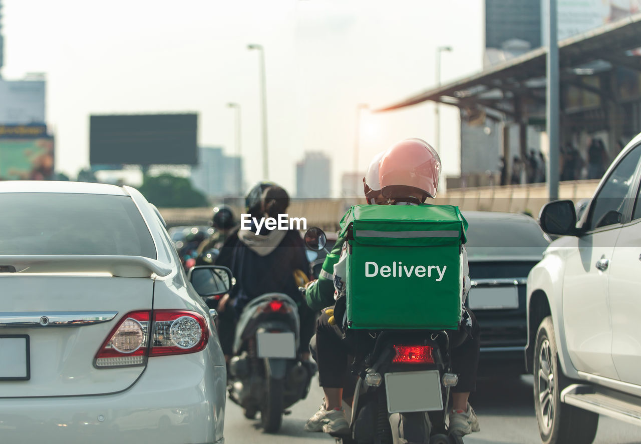 rear view of man riding motor scooter on street