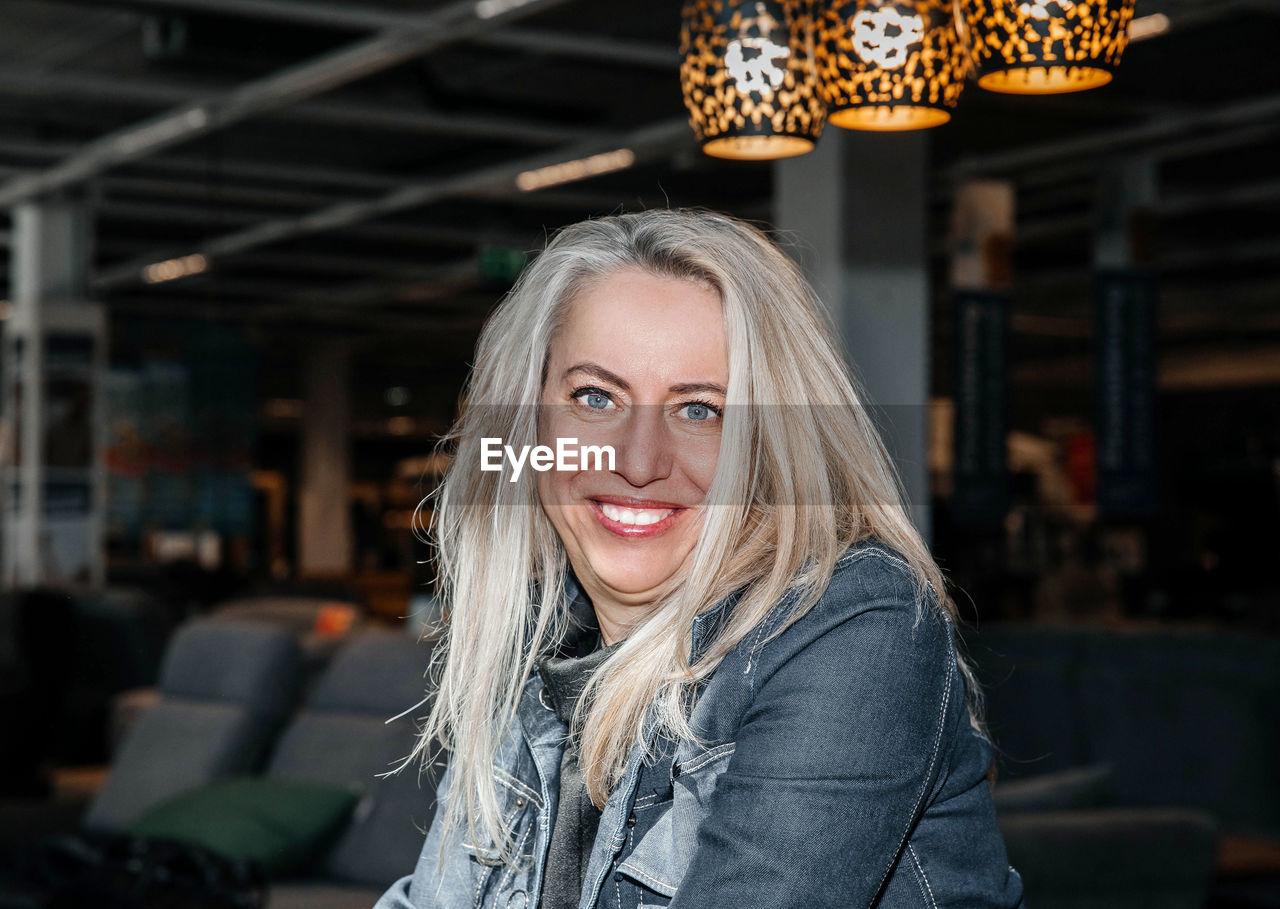 Radiant woman with lustrous blonde hair smiling in a chic showroom