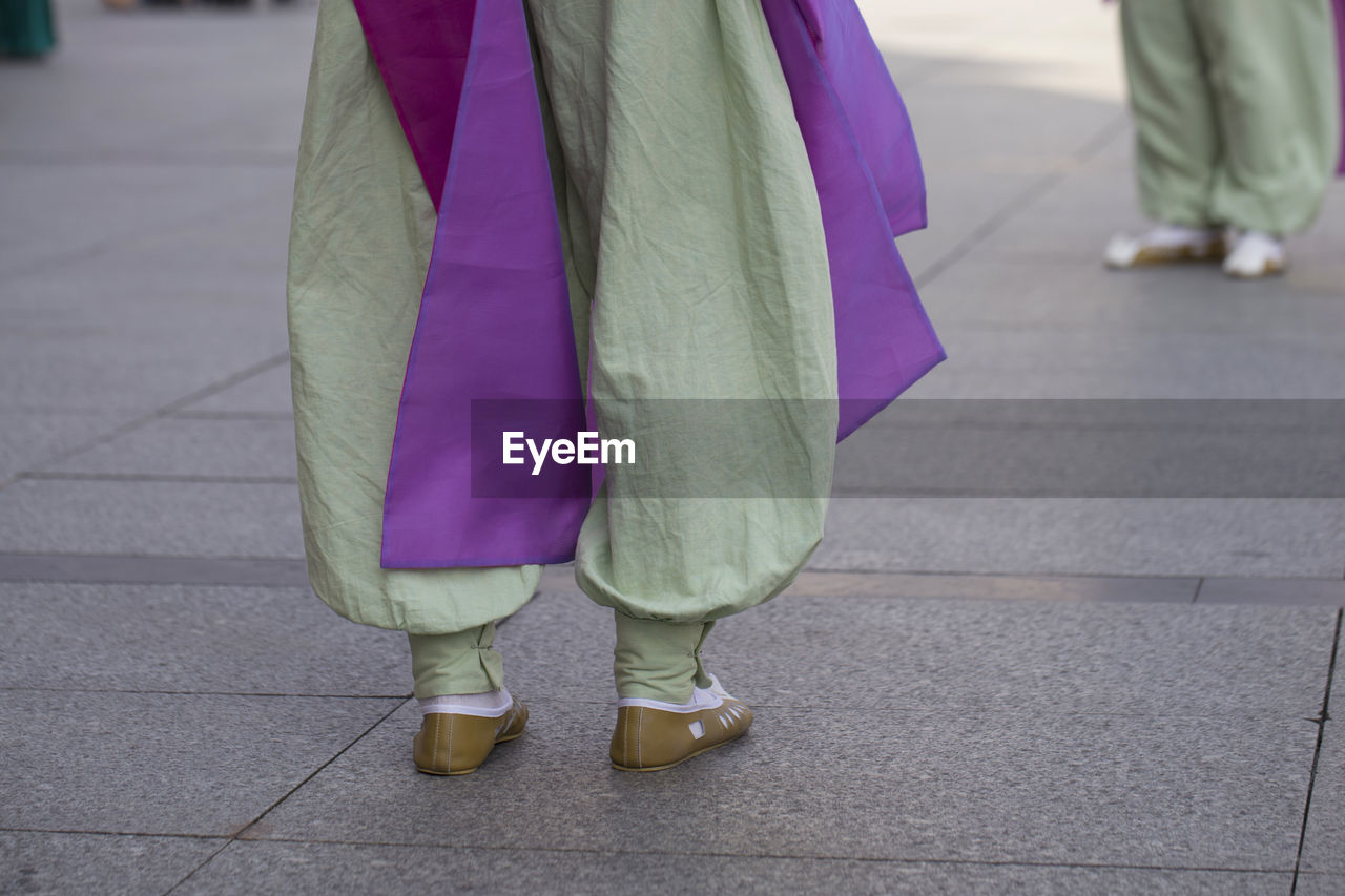 Low section of woman standing on footpath