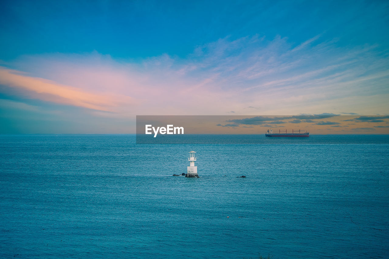 High angle view of lighthouse in sea against cloudy sky